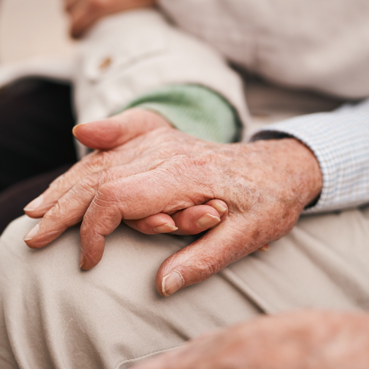 Two people holding hands, one elderly, in a close-up shot.